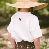 Close up back view of child wearing a kids Disney tee with embroidered Mickey Mouse on neck. 