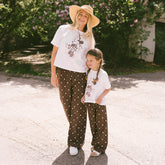 Woman and child standing outdoors wearing matching Disney outfits. 