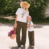 Mom and daughter wearing matching outfits for Disneyland—kids Minnie Mouse shirt and kid's Minnie Mouse pants standing in a garden. 