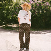 Woman standing in a garden wearing the perfect outfit for Disneyland—chic Minnie Mouse shirt and stylish women's Disney pants. 