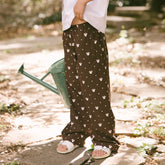 Child standing in a garden wearing kid's Disney pants—brown wrinke-free kids pants in Minnie Mosue print are perfect for Disneyland. 
