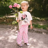 Child holding pink roses in a garden wearing a pink Minnie Mouse outfit for kids 