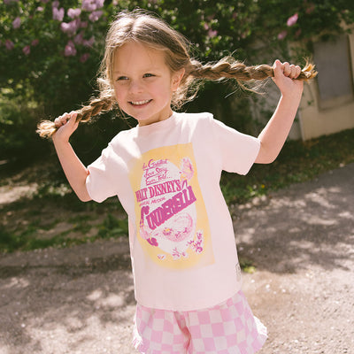 Young girl with braided pigtails wearing a cute kids Cinderella t-shirt standing in a garden