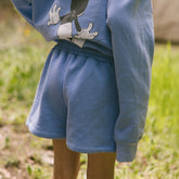 Close up back view of child wearing kid's Disney shorts in sky blue with matching kid's Disney hoodie. 