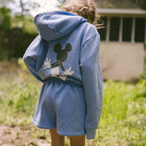 Child wearing kid's Disney matching set in sky blue with Mickey Mouse screen printed sweatshirt and shorts. 