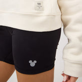 Close-up of black Disney Mickey biker shorts showcasing a Mickey graphic near the hem on a model