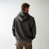 Man wearing a dark gray hoodie from behind on a plain background