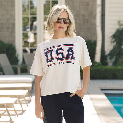 Woman wearing a USA T-shirt—the perfect 4th of July shirt for women in white with screen printed USA 1776 logo.