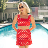 Woman in a red and white star-patterned two-piece swimsuit standing by a pool.