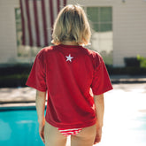 Person wearing a red shirt with a white star in front of a pool