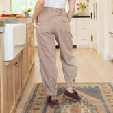 Back view of woman wearing brown gingham balloon pants in a modern kitchen setting.