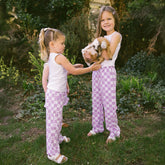 Two young girls standing outside in matching Disney outfits for kids—purple checkered kid's Disney pants with Minnie Mouse print