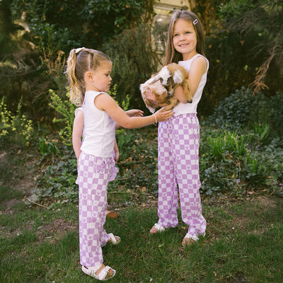 Two young girls standing outside in matching Disney outfits for kids—purple checkered kid's Disney pants with Minnie Mouse print