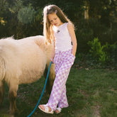 Young girl wearing a Minnie Mouse top with kids Minnie pants walking next to a small pony in a garden