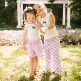 Two young girls in matching Disney outfits  for kids standing in a garden holding a baby chick.