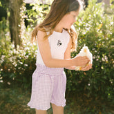 Young girl holding a small chicken in a garden setting and wearing a cute Disneyland outfit for kids. 