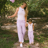 Woman and child on a garden path wearing matching outfits for Disneyland—kids Minnie Mouse tank top and kids Disney pants. 