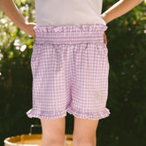 Purple checkered shorts worn by a child with a blurred green background