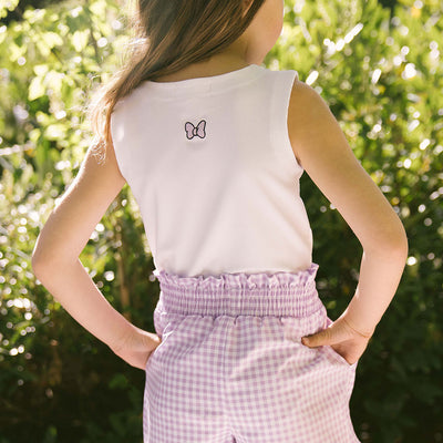 Child wearing a Disney shirt for kids—Minnie Mouse tank top for girls with purple gingham shorts. 