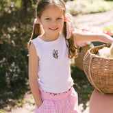 Child wearing a Daisy Duck shirt for kids with matching kids Disneyland bottoms in pink gingham on a blurred background