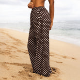 Person wearing a black polka dot skirt on a sandy beach.