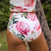 Floral high-waisted bikini with pink flowers and green leaves on a white background.