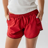 Front view of red polka dot varsity shorts on a model, showing the elastic waistband against a light gray background