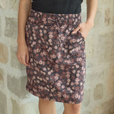 Women wearing a knee length skirt in brown floral print—a wrinkle-free skirt with pockets against a stone wall