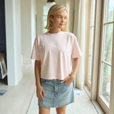 Woman wearing Albion's Perfect Tee—a light pink t-shirt and denim skirt.