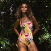 Woman wearing a yellow swimsuit with pink floral pattern in a tropical setting