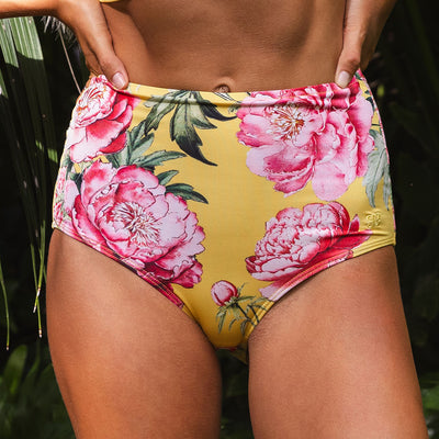 Floral high-waisted bikini bottom with pink flowers on a yellow background.