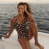 Woman in a polka dot swimsuit sitting on a boat with ocean in the background