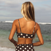 Woman in a polka dot bikini standing on a beach with ocean view