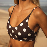 Woman wearing a brown bikini with white polka dots on a beach.