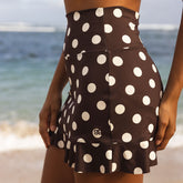 Person wearing a brown polka dot skirt on a beach