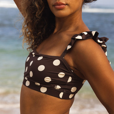 Woman wearing a brown bikini with white polka dots on a beach.