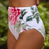 Floral high-waisted bikini bottom with pink flowers and green leaves on a white background.