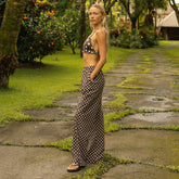 Woman in a polka dot outfit standing on a stone path in a garden.