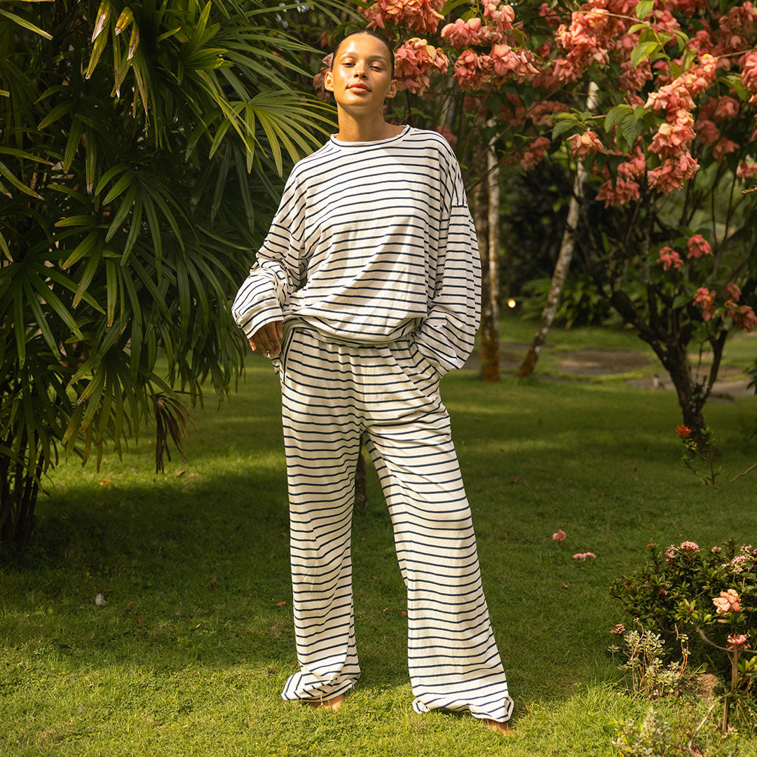 Woman wearing a navy blue striped matching set standing in a garden with greenery and flowers.