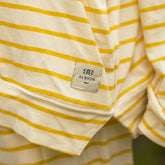 Close-up of a yellow and white striped shirt with a Albion brand label on a blurred background
