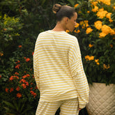 Back view of woman wearing a striped long sleeve tee standing in front of flowers