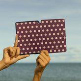 Polka dot tablet held by hands with ocean in background