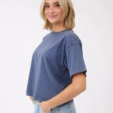 Three-quarter view of blue oversized cotton tee showcasing relaxed fit on model against a white background