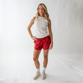 Front view of red polka dot varsity shorts worn by a model in a white studio