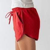 Side view of red polka dot Varsity Shorts showcasing elastic waistband, drawstring, and side pocket on a model
