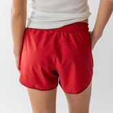 Rear view of red polka dot Varsity Shorts showcasing an elastic waistband and curved hem on a model