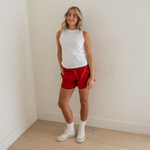 Front view of red polka-dot Varsity Shorts worn by a model with a white sleeveless top against a neutral wall