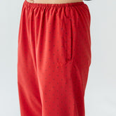 Close-up front view of red polka dot slip-on trousers showcasing elastic waistband and drawstring on light background