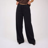 Woman wearing black wide-leg pants for women on a white background