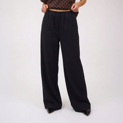 Woman wearing black wide-leg pants for women on a white background